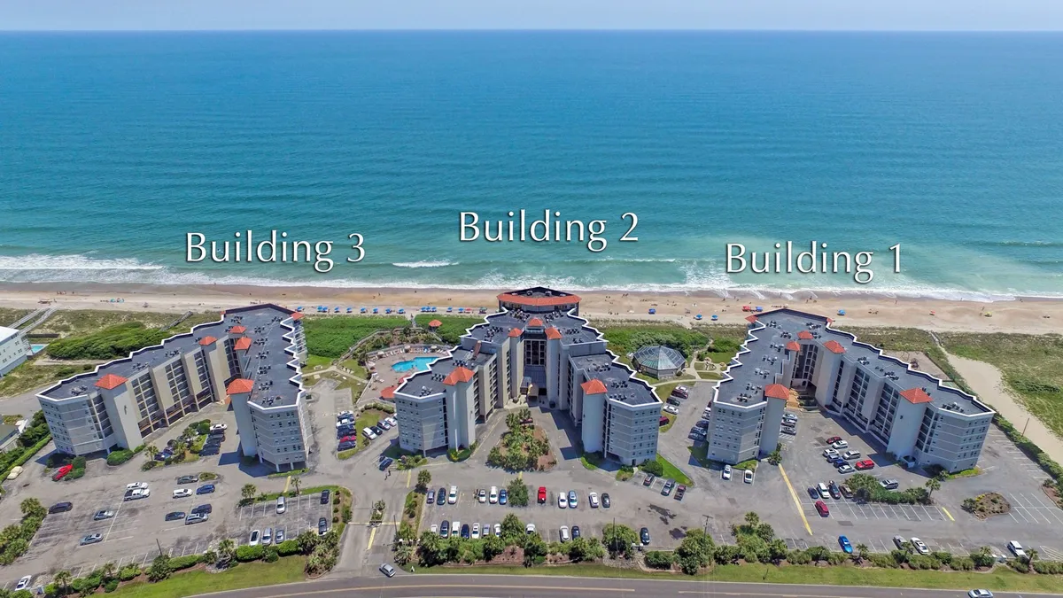 Three main resort buildings sit beside a spacious swimming pool area, all oriented toward a sparkling ocean. The environment is lively yet relaxing, ideal for family gatherings, swimming, sunbathing, and easy access to the beach—all essential elements of a group escape.