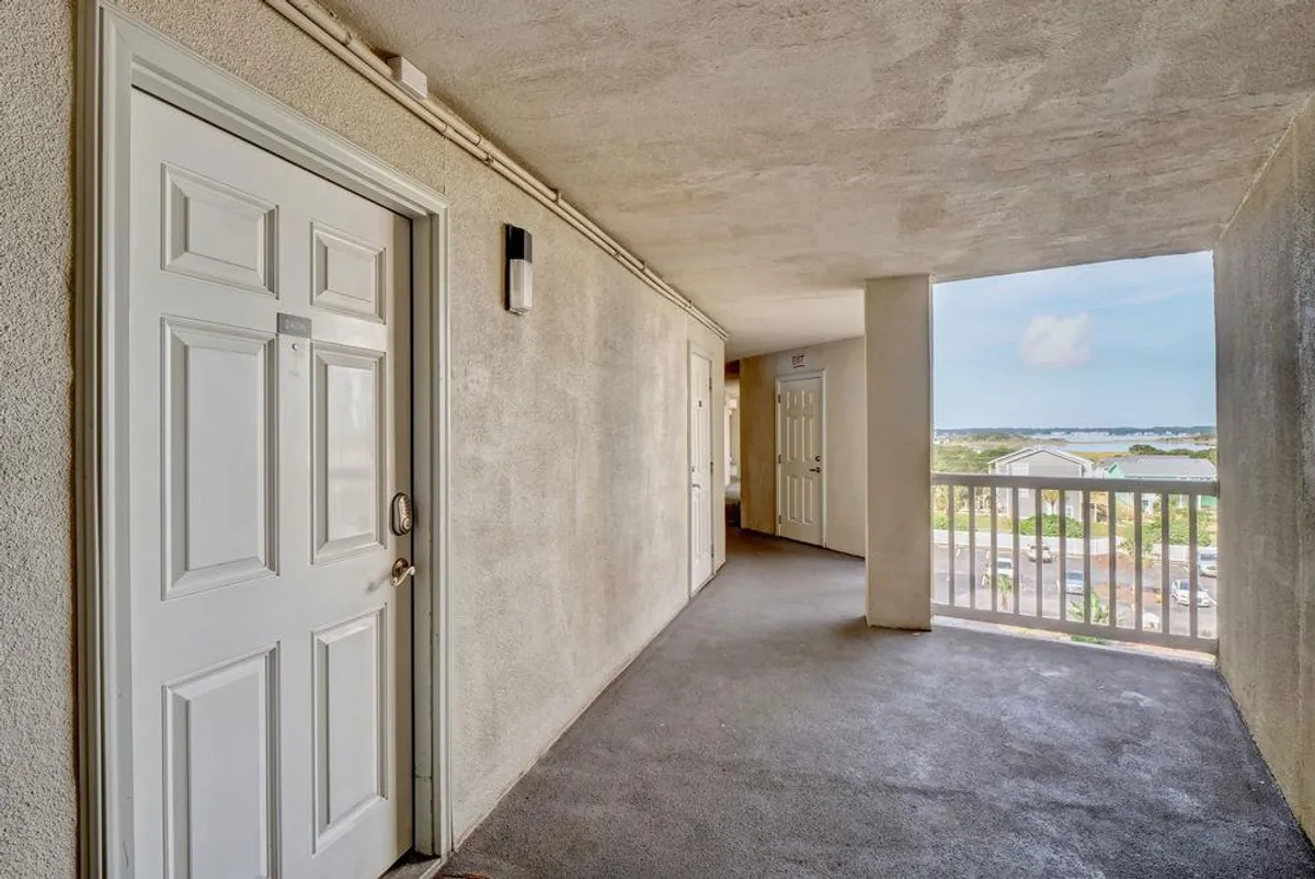 A welcoming hallway with the front door open, offering a glimpse of the outdoors. Soft natural light spills inside, inviting guests to explore both the home and the surrounding area. The decor is warm and inviting, with subtle beach-themed touches.