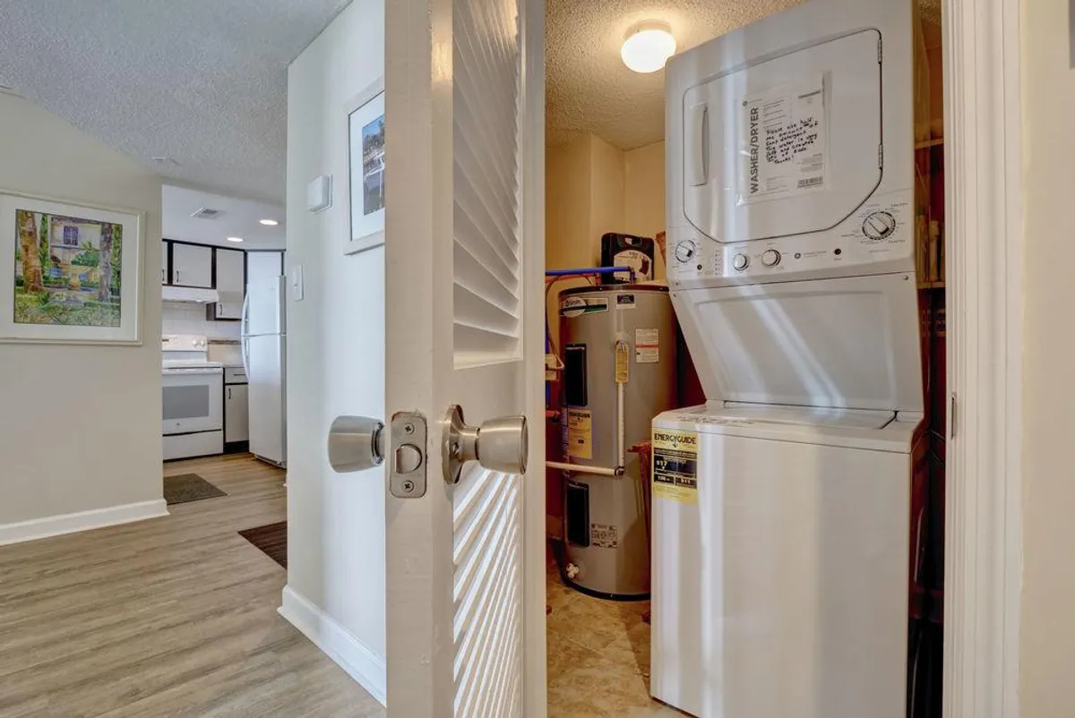 A practical laundry area featuring a washer and dryer, water heater, and framed artwork. The space is clean and organized, emphasizing convenience and home-like amenities.