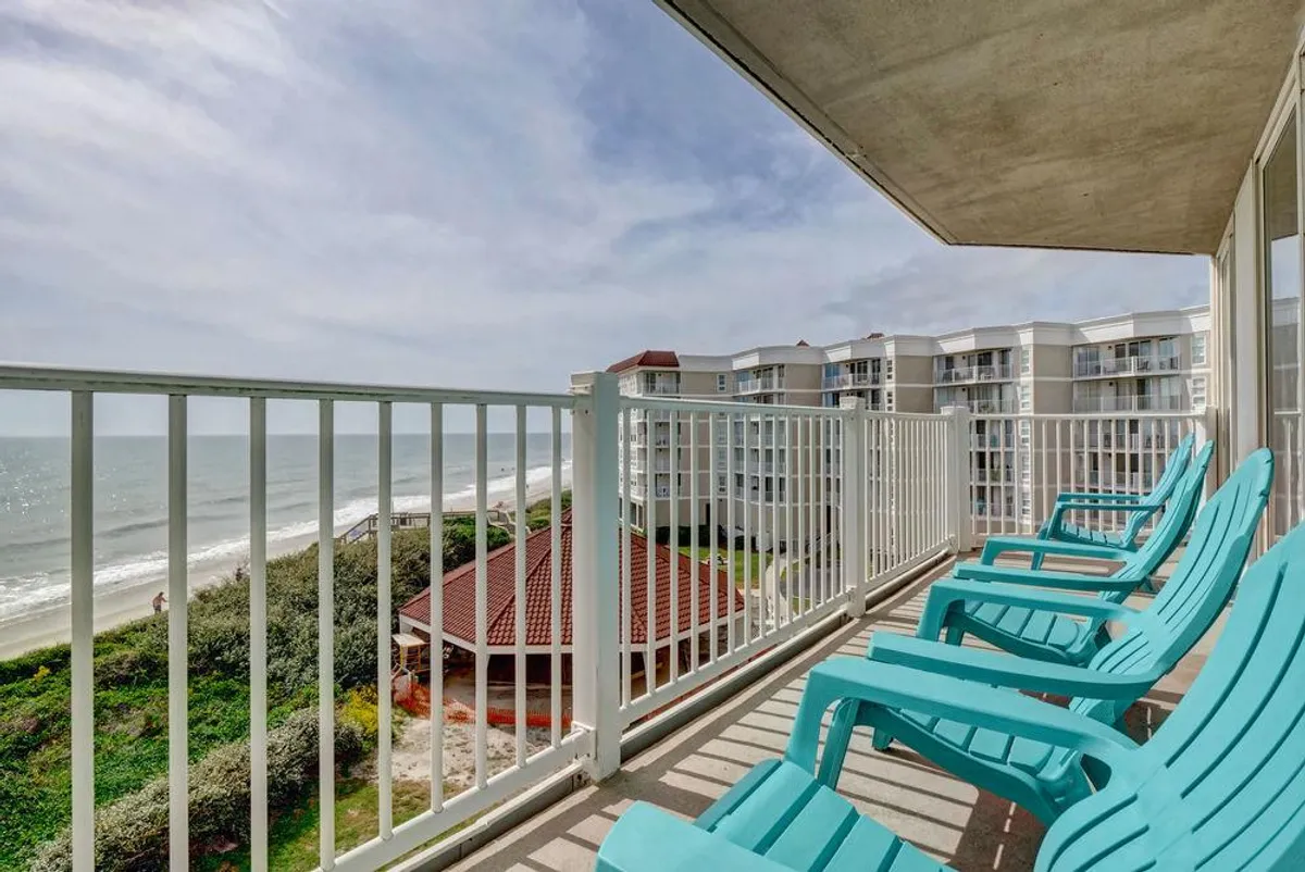 A private balcony with comfortable seating overlooks an expansive ocean view, with the coastline stretching into the distance. The tranquil setting invites socializing, relaxing, and soaking in sunsets or early morning light, aligning with group activities and shared moments highlighted in the section.