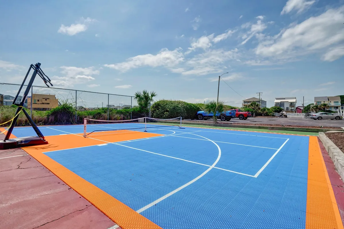 An energetic and colorful outdoor basketball and tennis court nestled among lush greenery. The court is ready for games or casual workouts, with sunlight highlighting the playful vibe of the space.